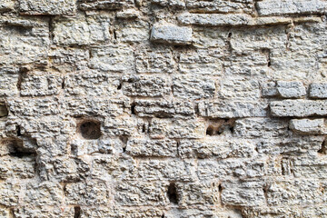 Fragment of ancient medieval fortress wall made of limestone. Vintage background. Natural old stone. Pattern in medieval style. Elements of medieval architecture. Selective focus.