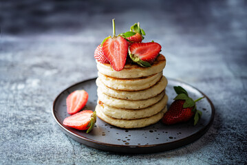 Pancakes decorated with strawberries in a plate
