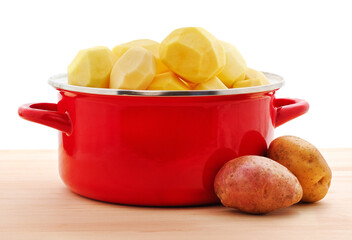 Peeled potatoes in a red saucepan.