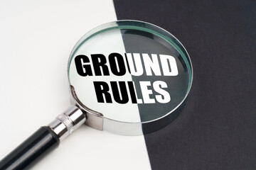 On the surface, which is half black and white, lies a magnifying glass inside which is written - GROUND RULES