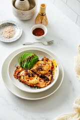 Fried Chili Spicy Egg Breakfast with Fresh Avocado on White Kitchen Background