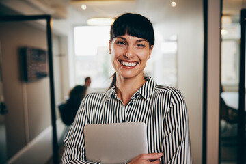 Smiling businesswoman carrying a laptop at work