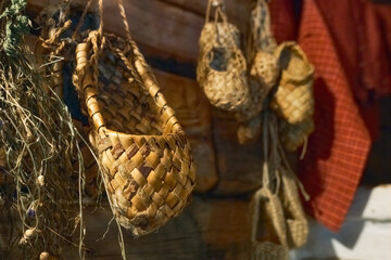 Woven bast shoes hang on the wall in the sun.