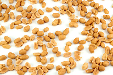 Scattered peeled salted peanuts isolated on white background. Top view.