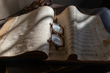 Antique glasses lie on the yellow sheets of the score