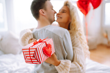 Valentine's Day concept. Exchange of gifts. Beautiful young couple at home celebrating Valentine's Day. Romantic day.
