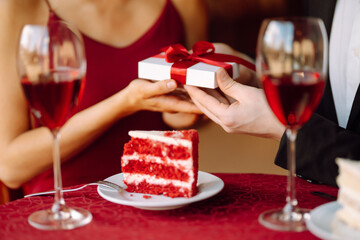 Valentine's Day concept. Exchange of gifts. Beautiful young couple celebrating Valentine's Day  in the restaurant. Hug, kiss and enjoy spending time together.