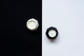two handmade soy wax candles in plaster candlesticks on a white and black background like yin yang