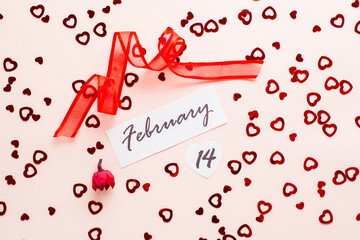 Valentine's Day. Date of February 14, dry flower and red ribbon on pink heart-strewn background