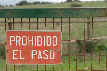 Señal de prohibido el paso en español, en una puerta de metal