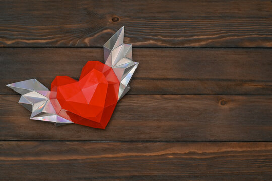 Polygonal heart with wings on a wooden background.