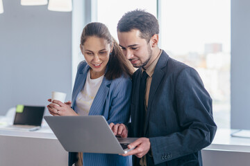 Employees stand in the office and use the laptop