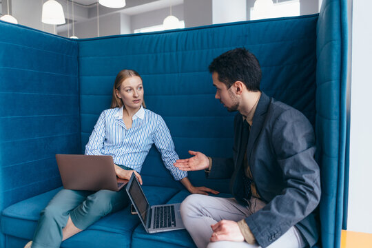 Employees on break sitting with laptops talking about business informally - Powered by Adobe
