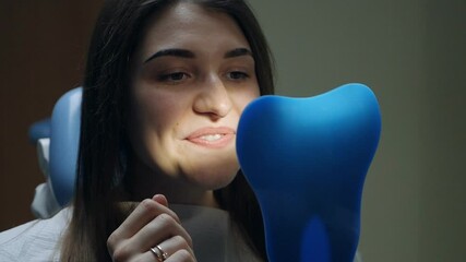 Young female patient trying on aligners looking in the mirror at the dentist's office