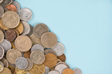 Variety of old coins on light blue background with copy space. Various vintage coins from worldwide as background. Financial growth and business concept. Numismatics and coin collecting