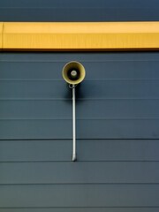 a loudspeaker against a yellow - gray - blue wall