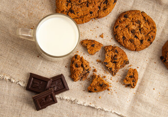 Homemade chocolate chip cookies and milk in a mug is located on a gray cloth