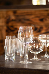 the glasses are empty and transparent, standing on a wooden bar counter, taken in natural light during the daytime