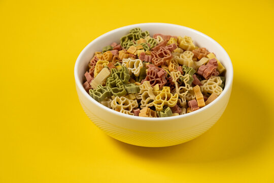 Pasta trottole tricolore wheat in a plate isolated on yellow background
