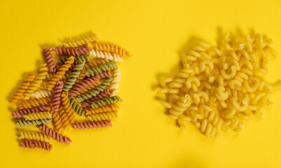 Close up of several types of dry pasta on yellow background