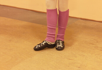 Irish dancer in soft shoes and purple leggings on a wooden floor, legs close up. Irish folk dancing