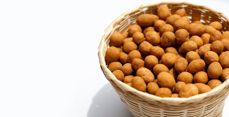 Crispy peanut snack balls in bamboo basket on white background.
