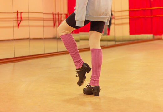 a teenage girl in special hard shoes and purple socks does exercises in front of a mirror, lifestyle, moves her leg and defocuses. Irish dance classes