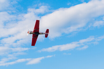 Small retro airplane, light aircraft flying in blue cloudy sky and doing stunts at Air Show....