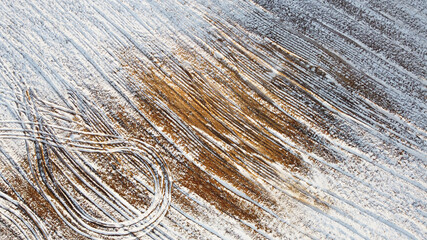 Photo from above on a landscape of a snowy field with sand. Winter texture