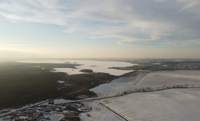 Top view photo of a winter suburban landscape with snowy fields, meadows and forests