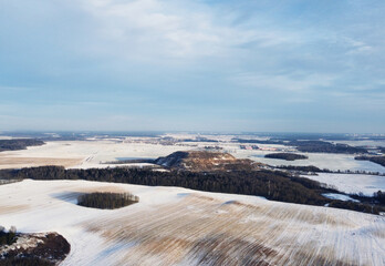 Top view photo of a winter suburban landscape with snowy fields, meadows and forests
