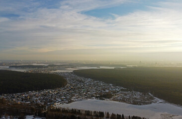 Top view photo of a winter suburban landscape with snowy fields, meadows and forests