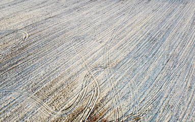 Photo from above on a landscape of a snowy field with sand. Winter texture