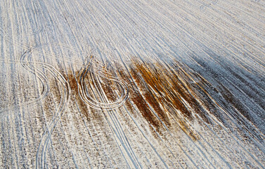 Photo from above on a landscape of a snowy field with sand. Winter texture