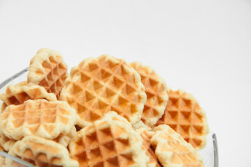 Belgian waffles in a glass bowl. holiday cookies on a white background. fresh baking concept. sweet desserts on a light texture