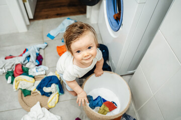 baby, mom's little helper scattered clothes in the bathroom, the boy helps mom to wash.