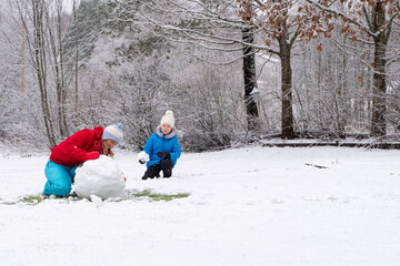 Depyat snowman in winter. A young woman and a 5-year-old child make a snowman. Fun and happiness...