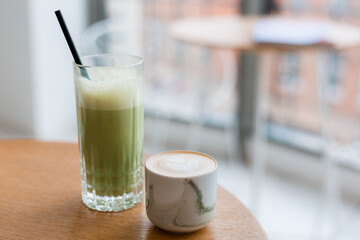 Matcha and Cup of cappuccino with latte art on wooden table in cafe. Concept of easy breakfast. Food banner