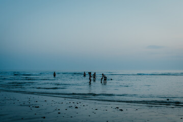 Fototapeta na wymiar Silhouetten von Menschen am Strand in der Abenddämmerung