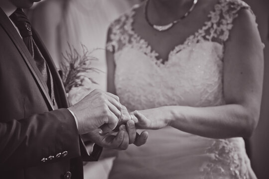 Homme qui passe la bague au doigt de sa femme lors d'un mariage
