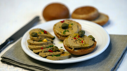 Liver pate with buns and spices on a plate.