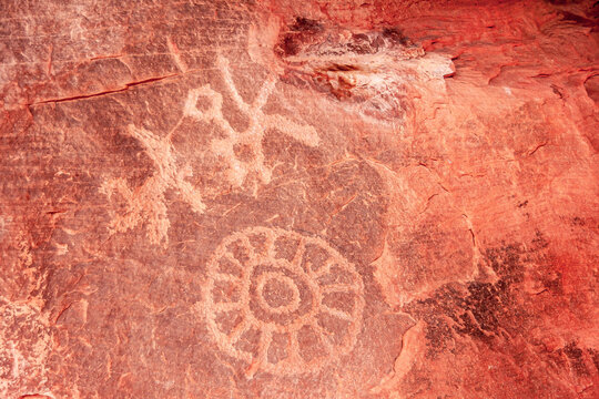 Overton, Nevada, USA - February 24, 2010: Valley of Fire. Closeup of ancient pictographic images of wheel or sun and maybe animal and human scratched on red roc surfaces in canyon. 
