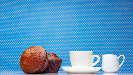 Morning breakfast with a cup of coffee and a muffin on a blue polka dot copy space background. Fresh cupcake with coffee.