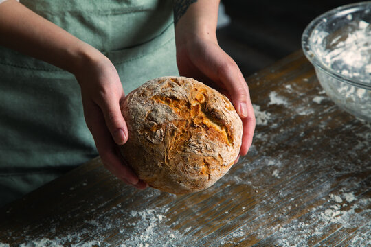 Baker Holding a Fresh Baked Artisan Bread Loaf