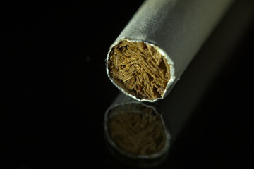 Cigarettes in macro close-up over black background with reflection. Harmful tobacco products.