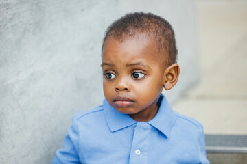 Sad one year old toddler almost preschool age African-American boy with big eyes looking away with copy space