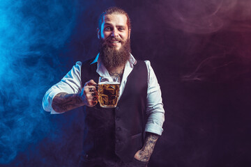 Positive bearded man holds tasty draft beer in hand. Drinking, Octoberfest concept. Smoke background