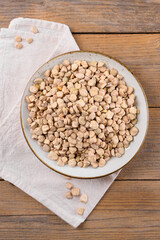 Dry raw cicerchia or indian pea on a ceramic plate with napkin on wooden background, top view, flat lay. Legumes known as Lathyrus Sativus, Chickling Vetch, Blue Sweet Pea