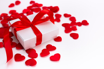 A white box with a gift in small red hearts on a white background, a template for Valentines day with a copy space, a postcard for February 14 with a place for text.