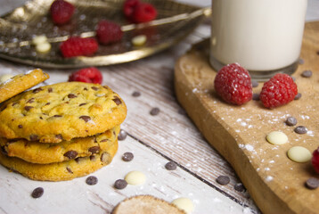 Baked biscuits with raspberries and milk with chocolate drops on the old wooden surface